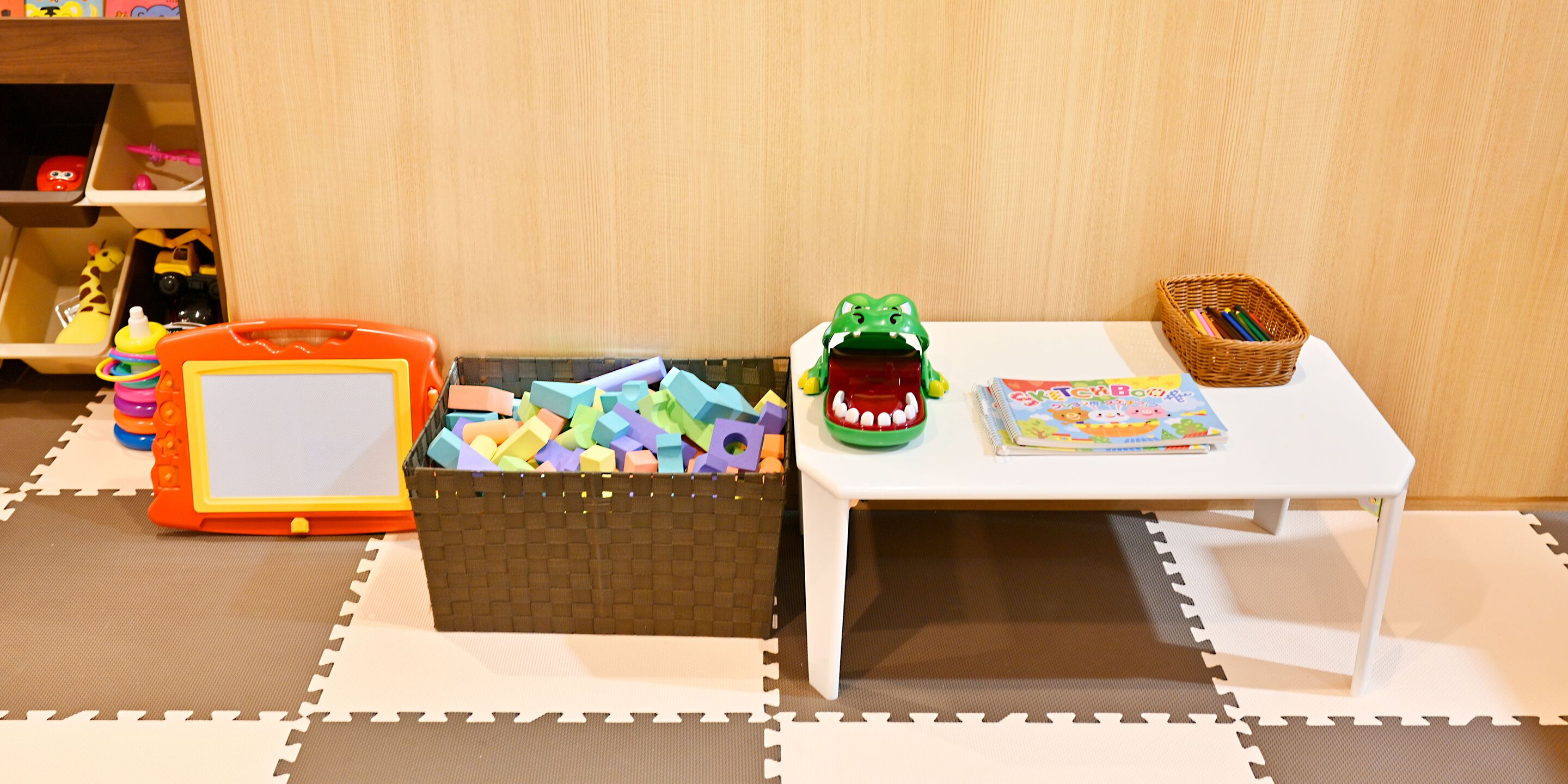 A play area with a white table, a basket of toys, and a toy car.