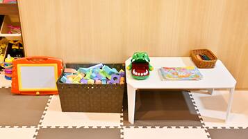 A play area with a white table, a basket of toys, and a toy car.