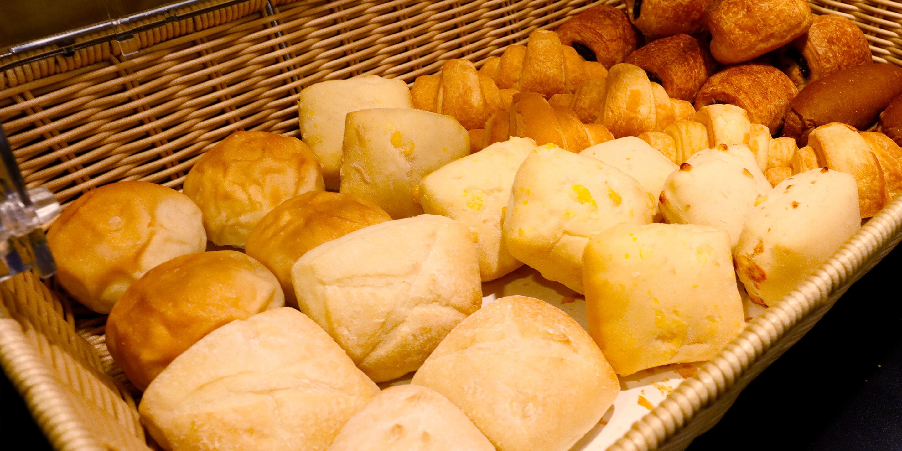 A wicker basket filled with various baked goods, including rolls and pastries.