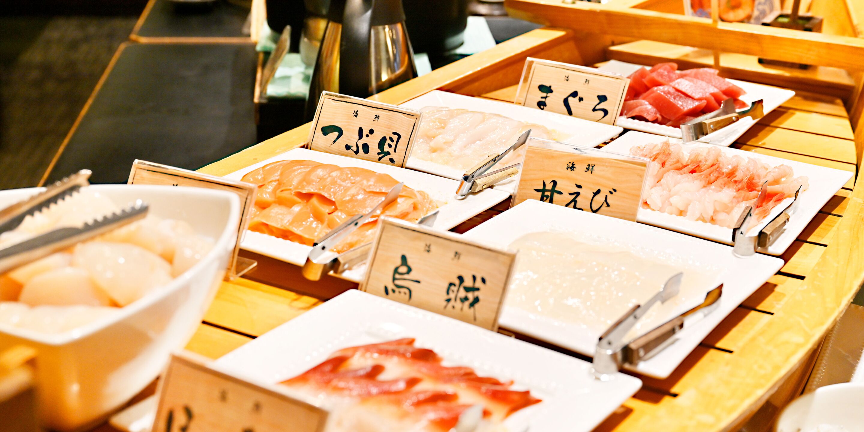 Diverse verse vis, gepresenteerd op houten schalen met labels, waarschijnlijk in een restaurant of op een markt.
