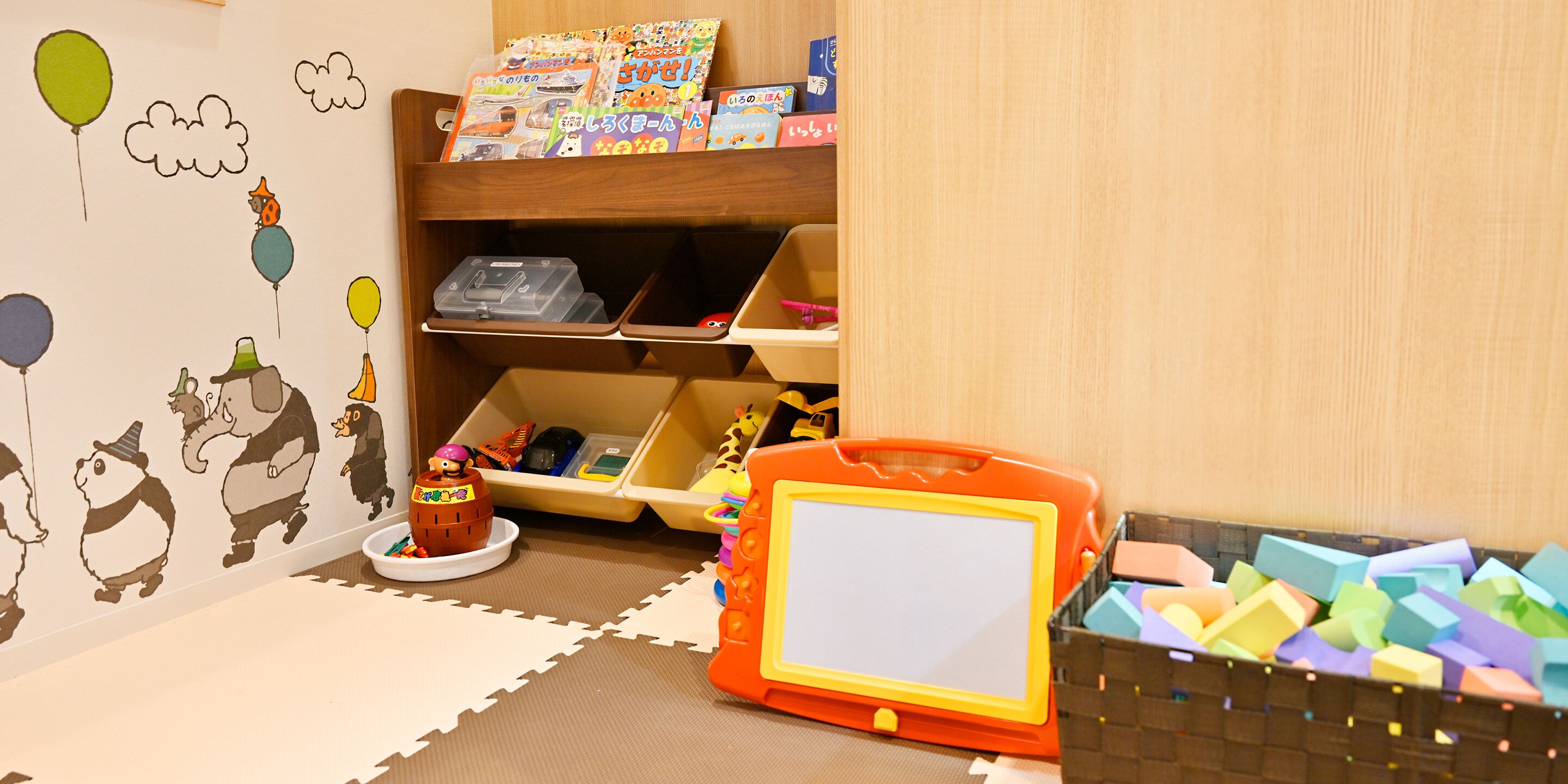 A child's play area with a shelf of books, a toy car, and a puzzle mat.