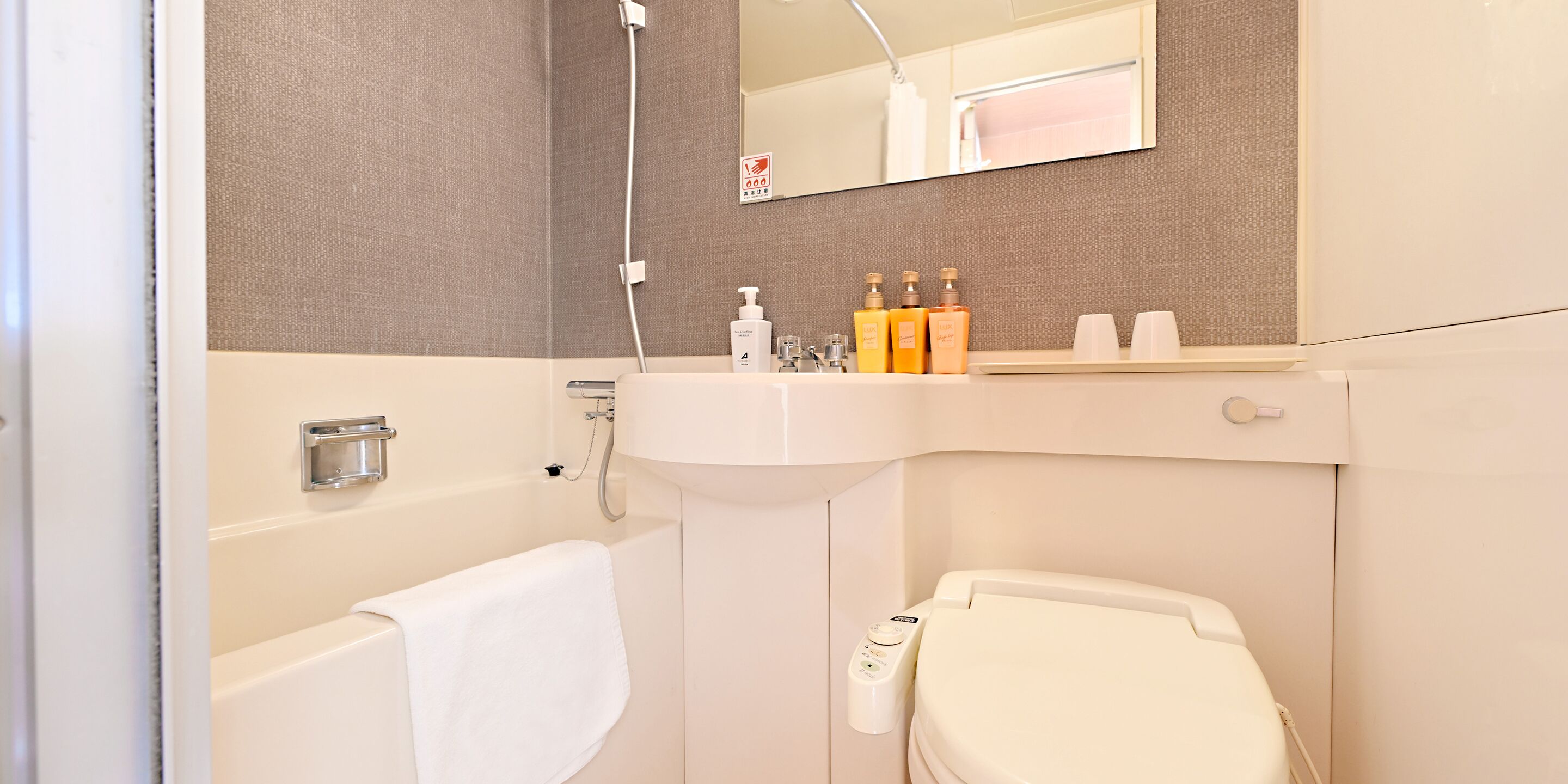 A bathroom with a bathtub, toilet, sink, and a mirror above the sink.