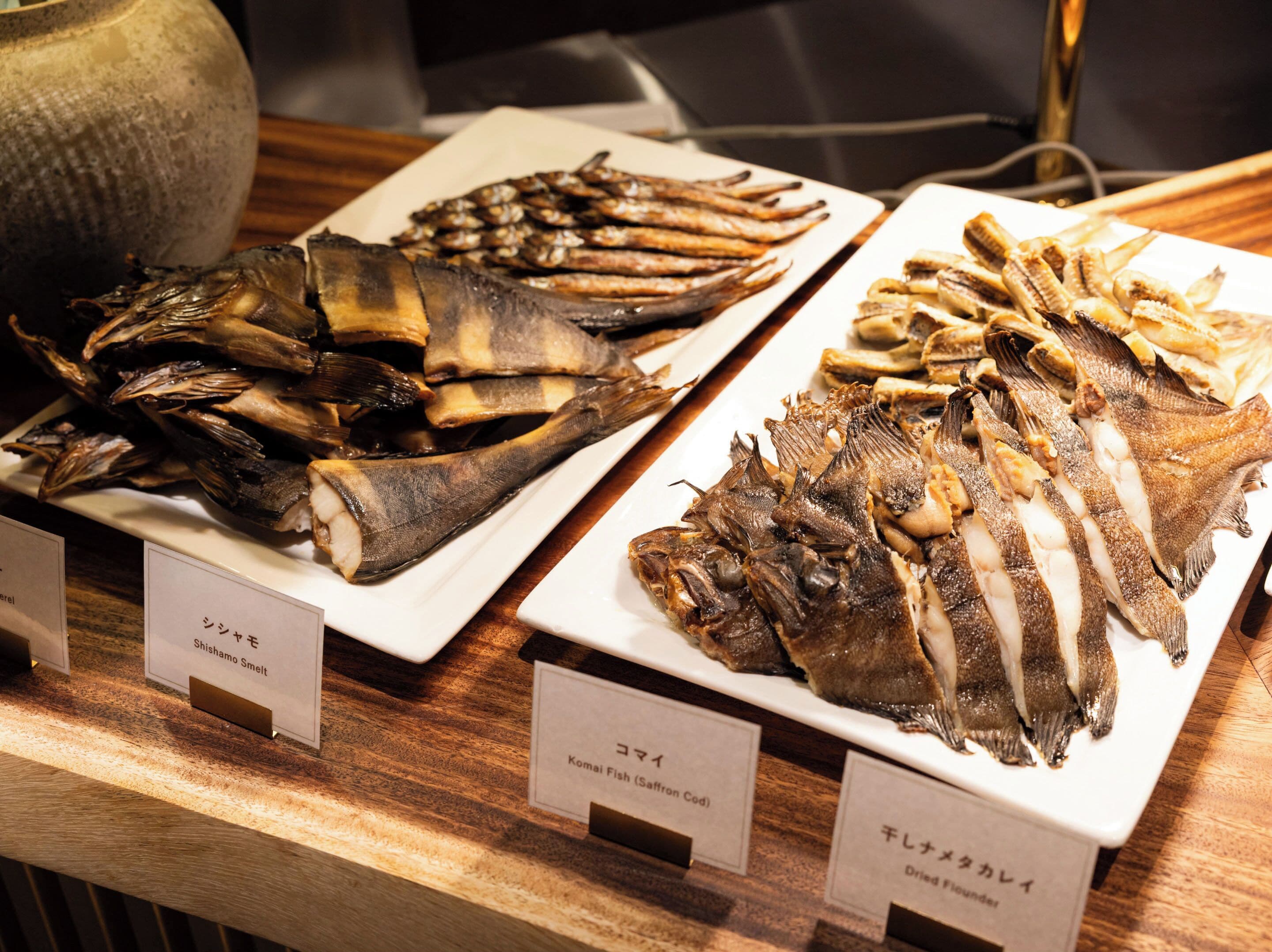 A display of dried fish on plates with labels in a restaurant.