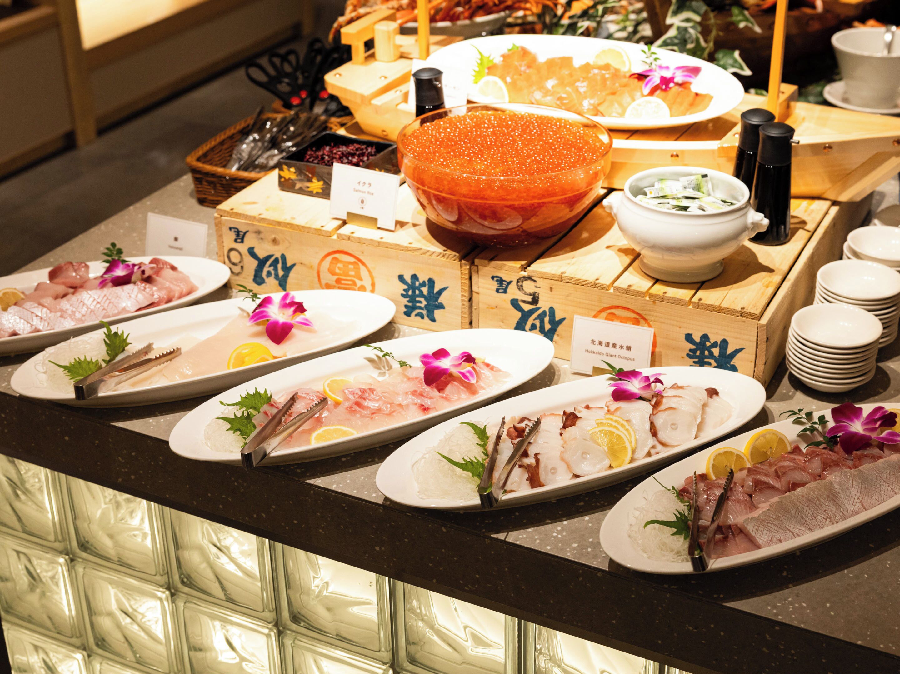 Een buffet met diverse zeevruchtengerechten, waaronder sashimi en sushi, gepresenteerd op een toonbank.