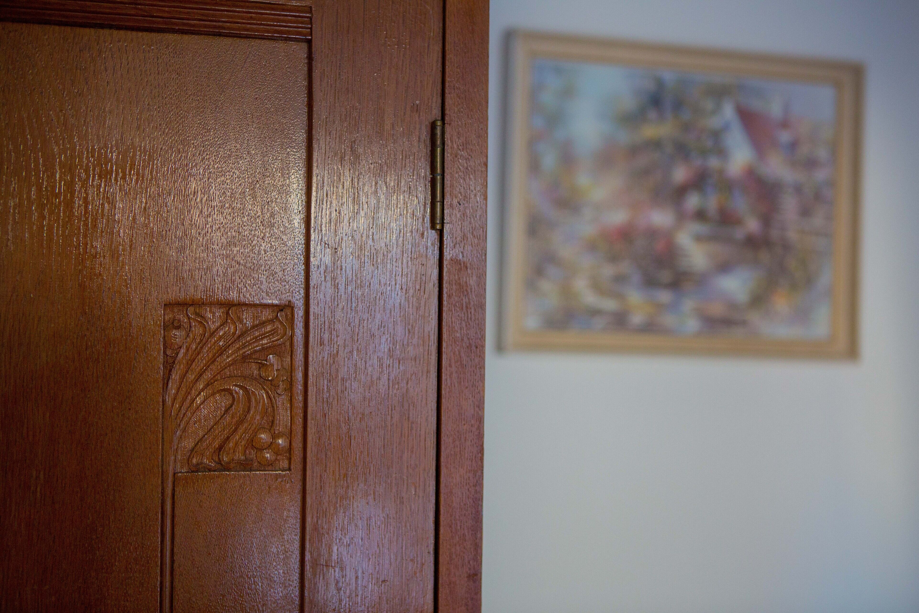Eine Holztür mit einer verzierten Tafel und einem gerahmten, abstrakten Gemälde an der Wand.