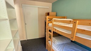 A bunk bed room with a door and a white shelving unit. - Cozy 2-room apartment at the foot of the slopes (Les Adrets-Prapoutel)