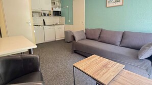A compact living space with a kitchenette, a sofa, a dining table, and a trash bin. - Cozy 2-room apartment at the foot of the slopes (Les Adrets-Prapoutel)