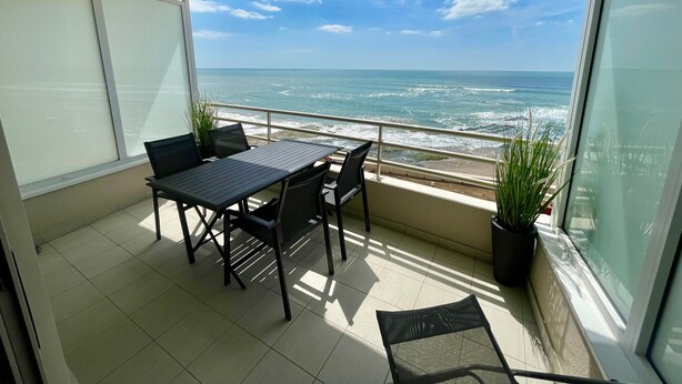 A balcony with a table and chairs, overlooking the ocean. - Modern sea-facing apartment with garage and free WiFi (Les Sables-d'Olonne)