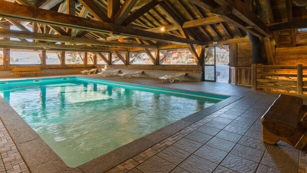 An indoor swimming pool with wooden beams, tiled flooring, and lounge chairs. - T3 Apartment in Les Saisies, 6 people, parking included (Les Saisies)