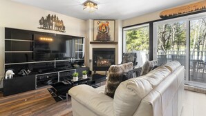Een moderne woonkamer met een open haard, een grote televisie en een bank.