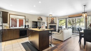 Een moderne keuken met een centraal eiland, een eethoek met tafel en stoelen, en een woonkamer met een bank en open haard.