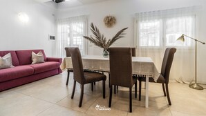 Un saló modern amb un sofà vermell, una taula de dinar amb quatre cadires i una làmpada de peu.