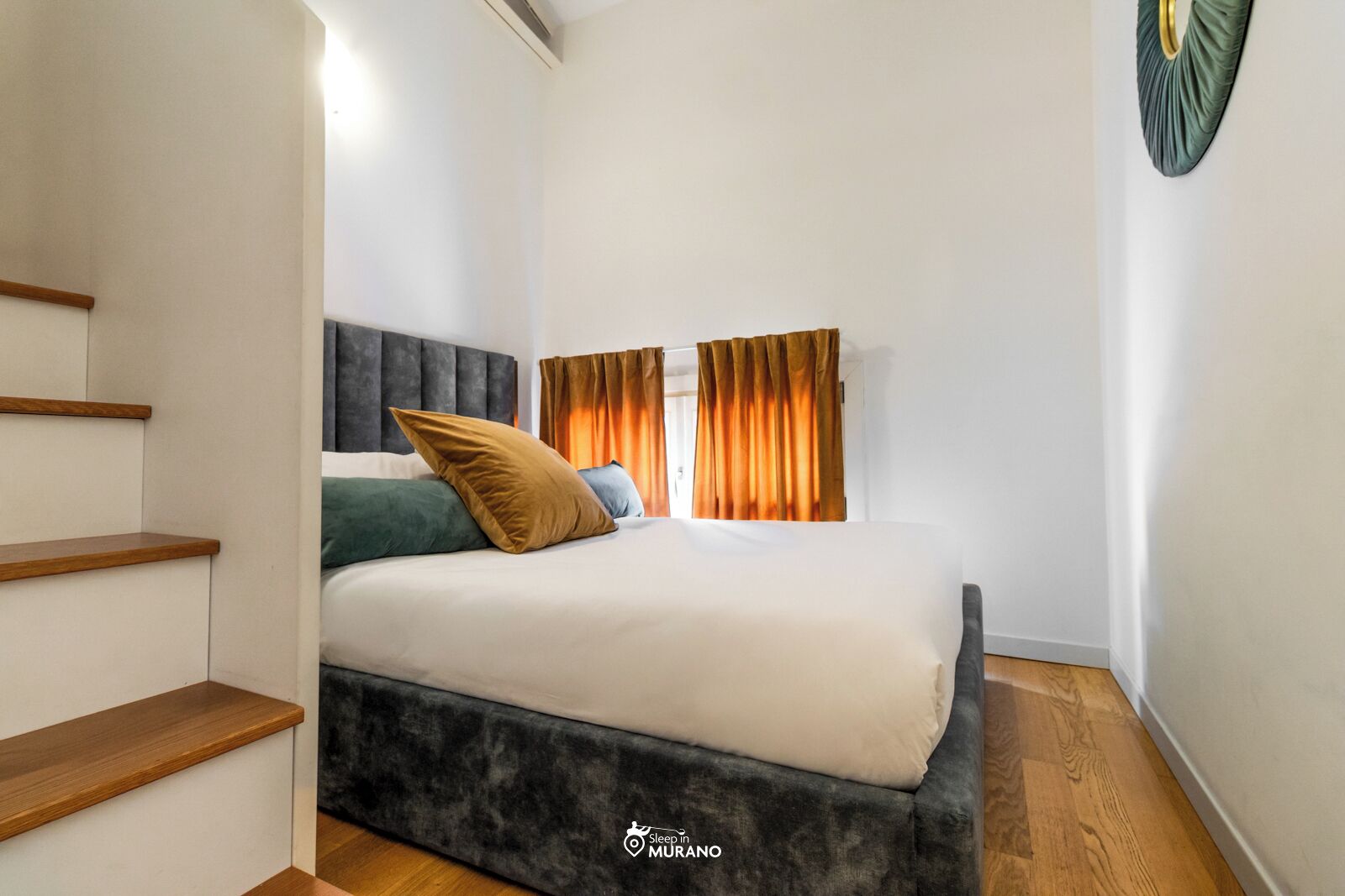 A bedroom with a bed, wooden staircase, and a headboard.