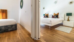 Un dormitori modern amb llit, taula de nit, làmpada i un mirall decoratiu.