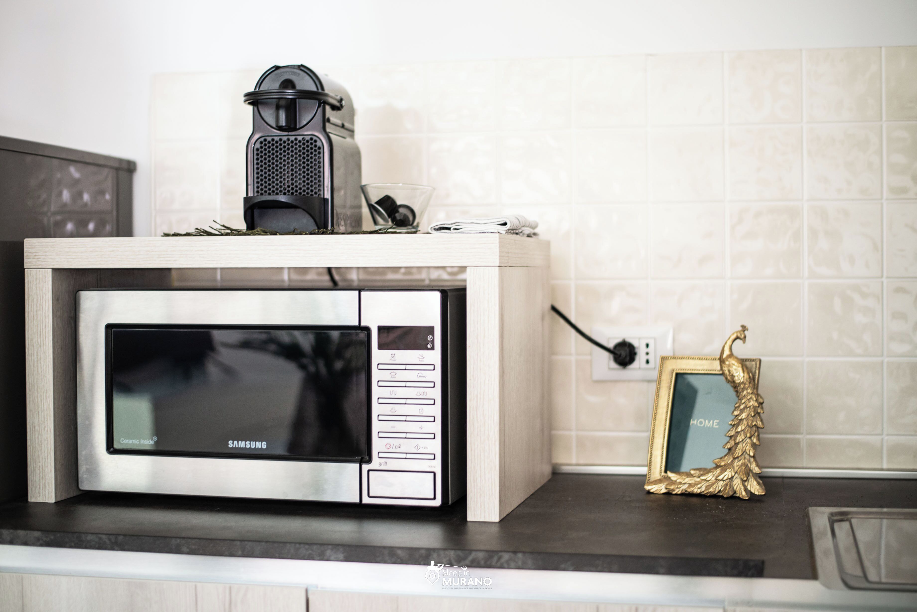 A kitchen with a microwave, a coffee maker, and a framed picture on the counter.