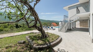 A modern building with a pool area, outdoor seating, and a staircase leading to the upper floors. - Vacation House With the Pool, Near River Cetina (Omis)
