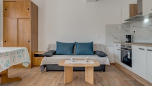 A compact living space with a sofa, a small table, a wooden wardrobe, and a kitchenette. - Vacation House With the Pool, Near River Cetina (Omis)