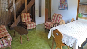 A room with a wooden staircase, two plaid armchairs, a wooden table with a white tablecloth, and a painting on the wall. - 4-room duplex with balcony and Wifi in Samoëns for 8 guests (Samoëns)