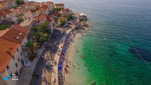 A coastal town with buildings along the waterfront, a clear beach, and people engaging in various activities. - Pirka - Apt. w. Terrace & sea View,2 min to Beach (Sutivan)