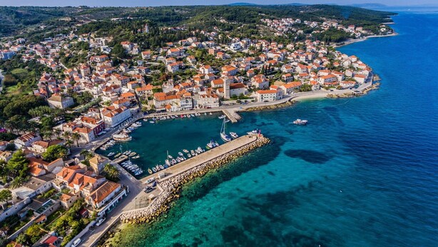 An aerial view of a coastal town with a marina, clear blue waters, and buildings with red-tiled roofs. - Pirka - Apt. w. Terrace & sea View,2 min to Beach (Sutivan)