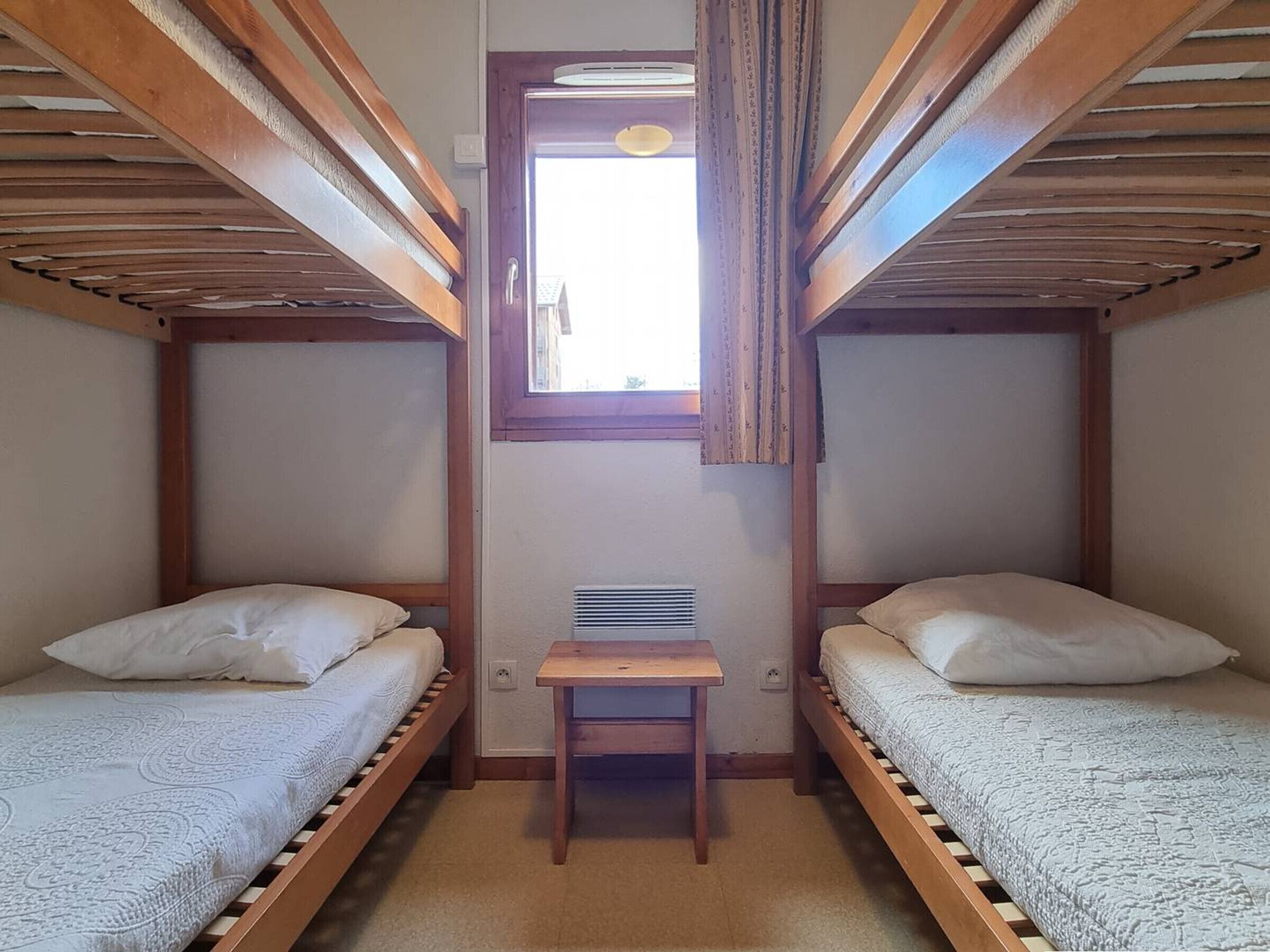 Quarto pequeno e compacto com duas camas beliche e uma escrivaninha.