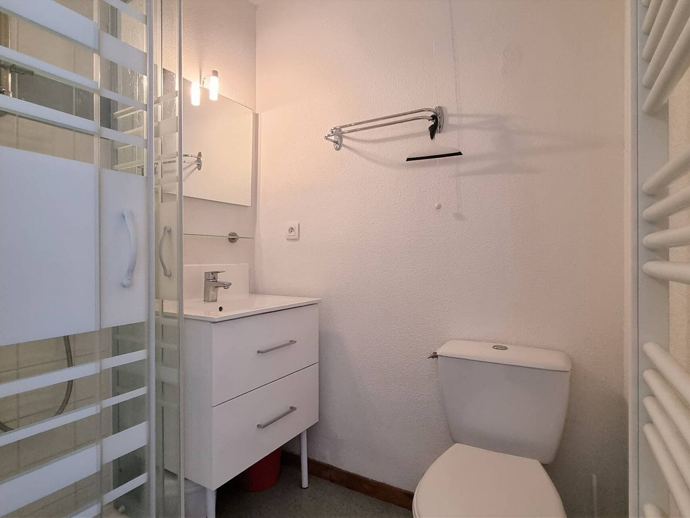 A bathroom with a white toilet, a sink with a mirror above it, and a towel rack on the wall.