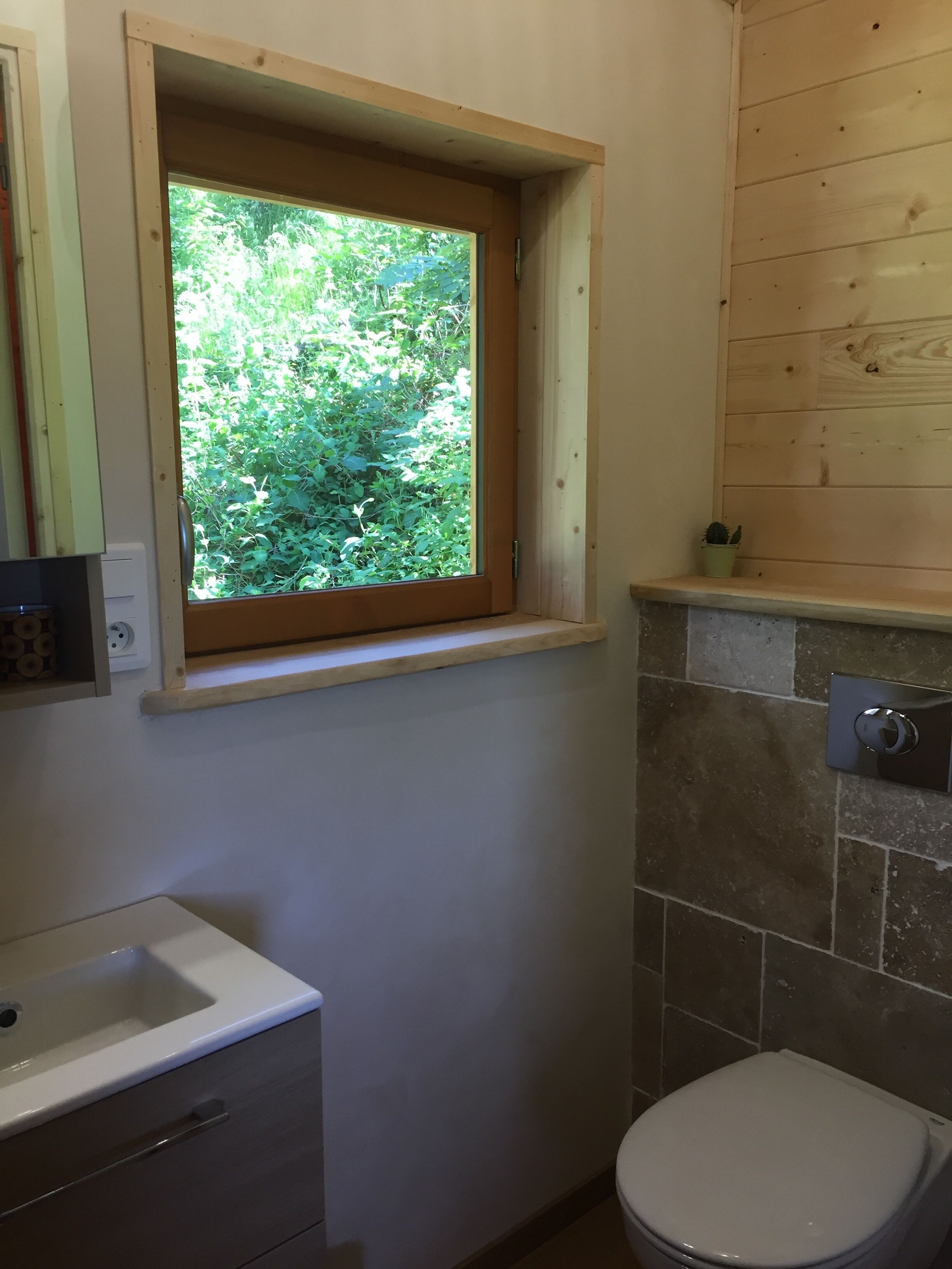 A bathroom with a window, a sink, a toilet, and a small potted plant. - Chalet - Lac Daydat (Aydat)