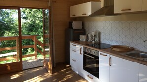 A modern kitchen with wooden cabinets, a built-in oven, a microwave, and a coffee maker. - Chalet - Lac Daydat (Aydat)