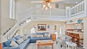 Ein geräumiges Wohnzimmer mit einem blauen Sofa, einem Holztisch und einer Treppe, die in eine obere Etage führt.