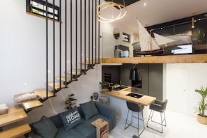 Experience the unique loft-style design with a spacious living area, cozy seating, and a compact kitchen.