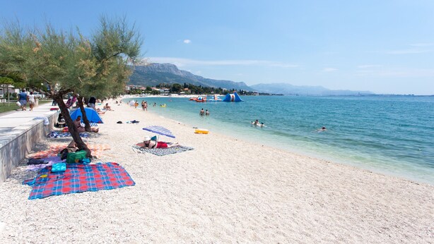 A beach with people sunbathing, swimming, and walking along the shore. - Beautiful, Modern Apartment Near the Sea, Croatia (Kastela)