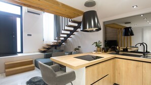 A modern kitchen with a wooden island, black pendant lights, and a built-in stove. - Beautiful, Modern Apartment Near the Sea, Croatia (Kastela)