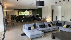 Ein modernes Wohnzimmer mit einem grauen Ecksofa, einem Couchtisch und einem Essbereich mit Stühlen und Tisch.