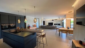 Eine moderne Küche mit Kochinsel, Barhocker und Pendelleuchten.