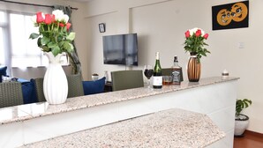 Un comptoir de cuisine avec une télévision, une bouteille de vin et deux vases de fleurs.