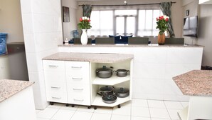 Une cuisine moderne dotée d’un plan de travail en granit, de meubles blancs et d’un porte-ustensiles intégré.