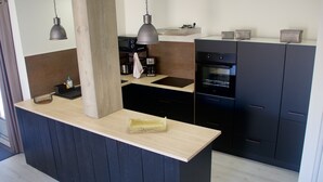 A modern kitchen with a central island, dark cabinetry, and a light countertop.