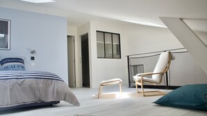 A modern bedroom with a bed, a chair, a bench, and a patterned rug.