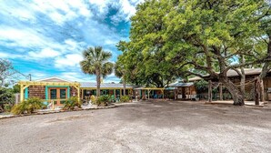 A building with a gravel driveway and a large tree in the center. - Surf's Up at Island Breeze of CB (Carolina Beach)