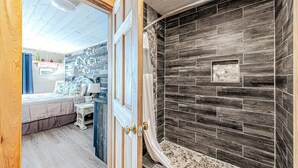 A bathroom with a shower area featuring dark wood paneling and a small decorative alcove. - Surf's Up at Island Breeze of CB (Carolina Beach)
