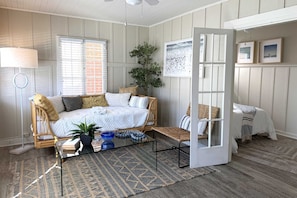 A cozy room with a bed, a sofa, a coffee table, and a door leading to another room.