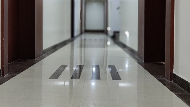 A long, well-lit hallway with a shiny floor and wooden doors on either side.