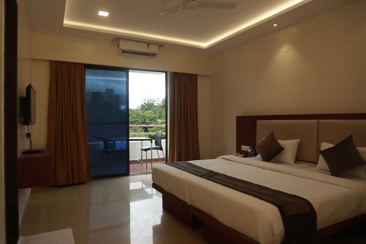 A hotel room with a large bed, a flat-screen TV, a ceiling fan, and a sliding glass door leading to an outdoor area.