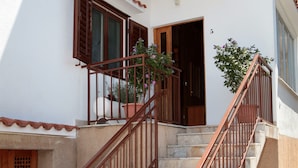 A staircase with a metal railing leading to a white building with a wooden door and window shutters. - Large Apartment w. big Terrace, Next to the Beach (Trogir)
