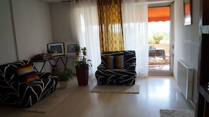 A living room with a sofa, armchair, and a small table with potted plants. - Beautiful spacious and bright apartment with large balcony (Montpellier)