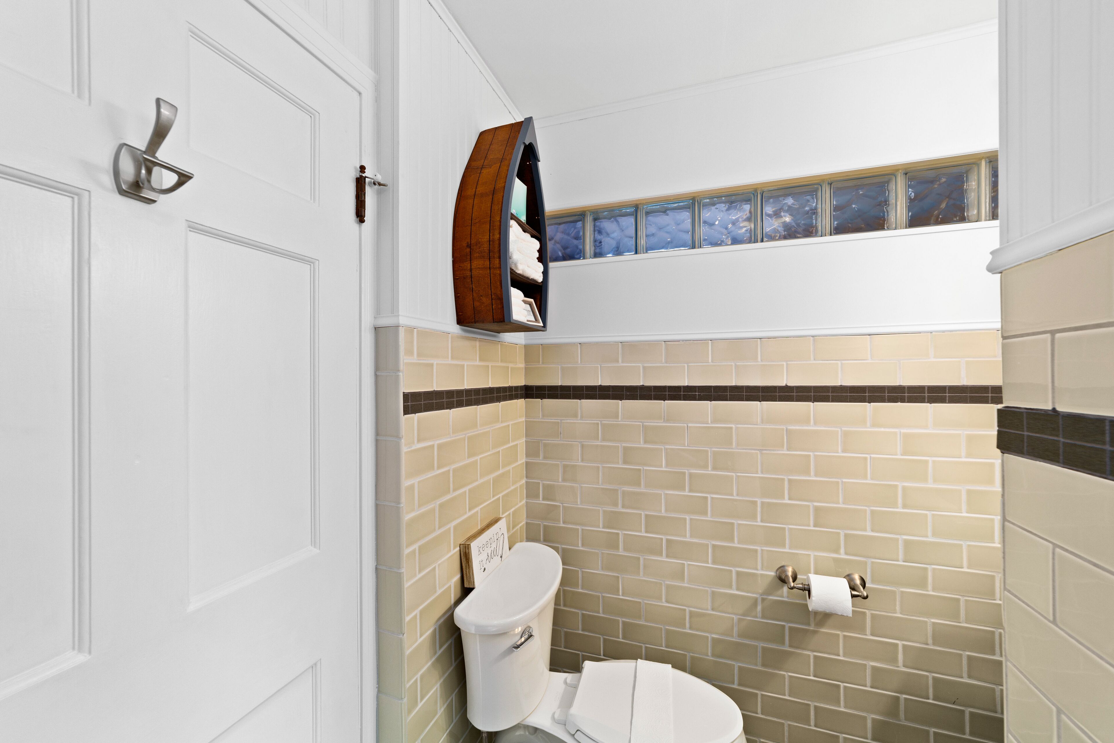 Un baño con inodoro, toallero y ventana sobre el lavabo.