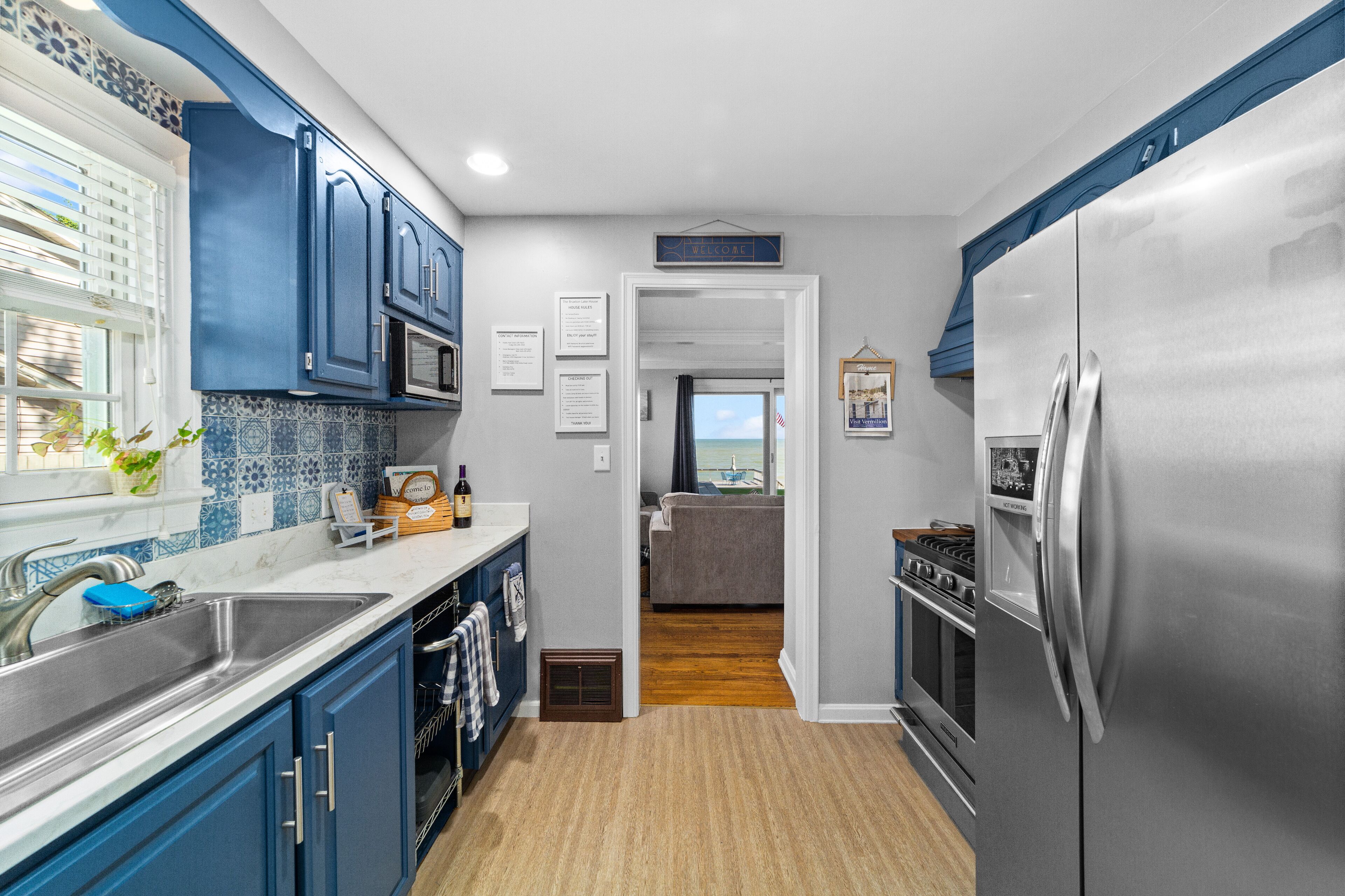A kitchen with blue cabinets, stainless steel appliances, and a view to the living area.