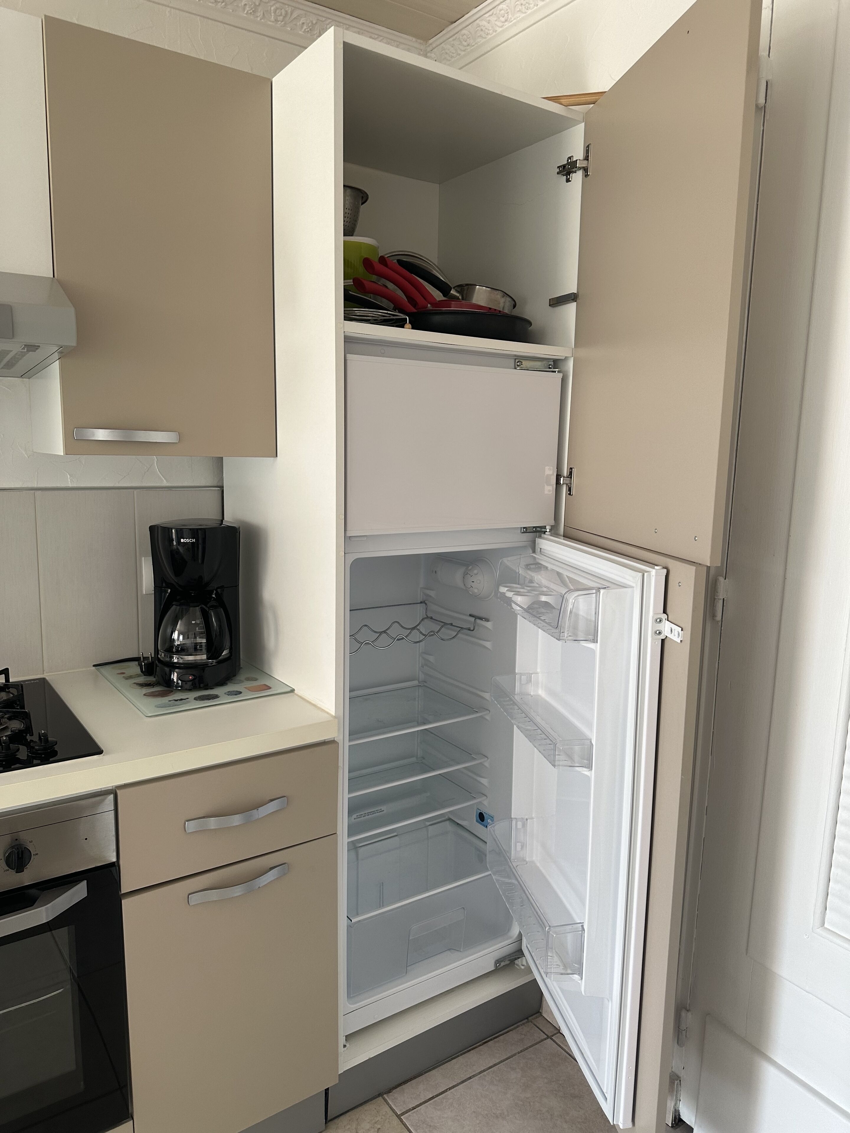 Una cocina con refrigerador empotrado, cafetera y estufa.