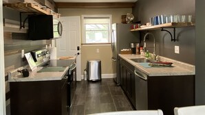 A modern kitchen with dark cabinetry, a central island, and a window. - Parkview at Cataract Falls Lodge.   (Spencer)
