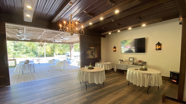 An indoor dining area with wooden floors, white round tables, and a chandelier. - Parkview at Cataract Falls Lodge.   (Spencer)